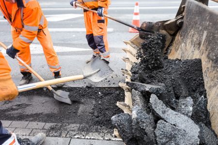 Robotnicy usuwający zniszczony asfalt z nawierzchni drogi