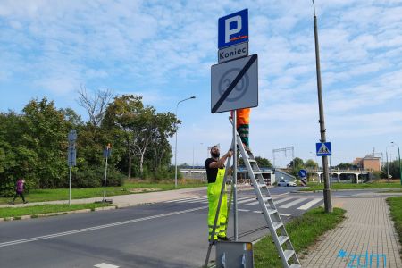 Pracownicy wymieniają znak drogowy prz ulicy