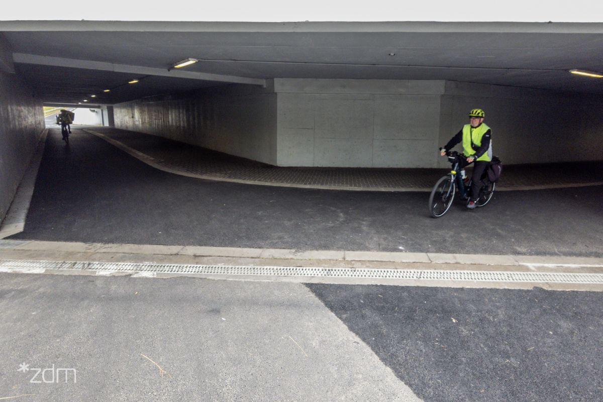 z lewej i prawej strony tunel z przejazdem rowerowo pieszym z prawej rowerzysta