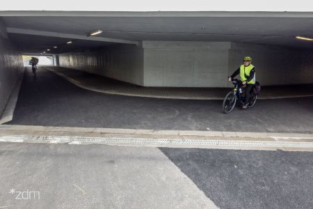 z lewej i prawej strony tunel z przejazdem rowerowo pieszym z prawej rowerzysta