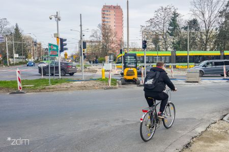 po lewej stronie skrzyżowanie ulic, na wprost budowa przejazdu rowerowego, widać koparkę, po prawej rowerzysta na jezdni, na drugim planie tramwaj