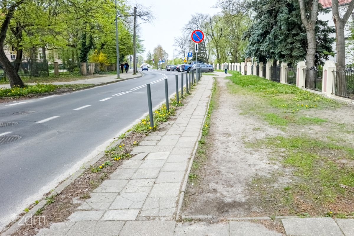 Chodnik z płyt betonowych, po prawej stronie pas zieleni, po lewej jezdnia