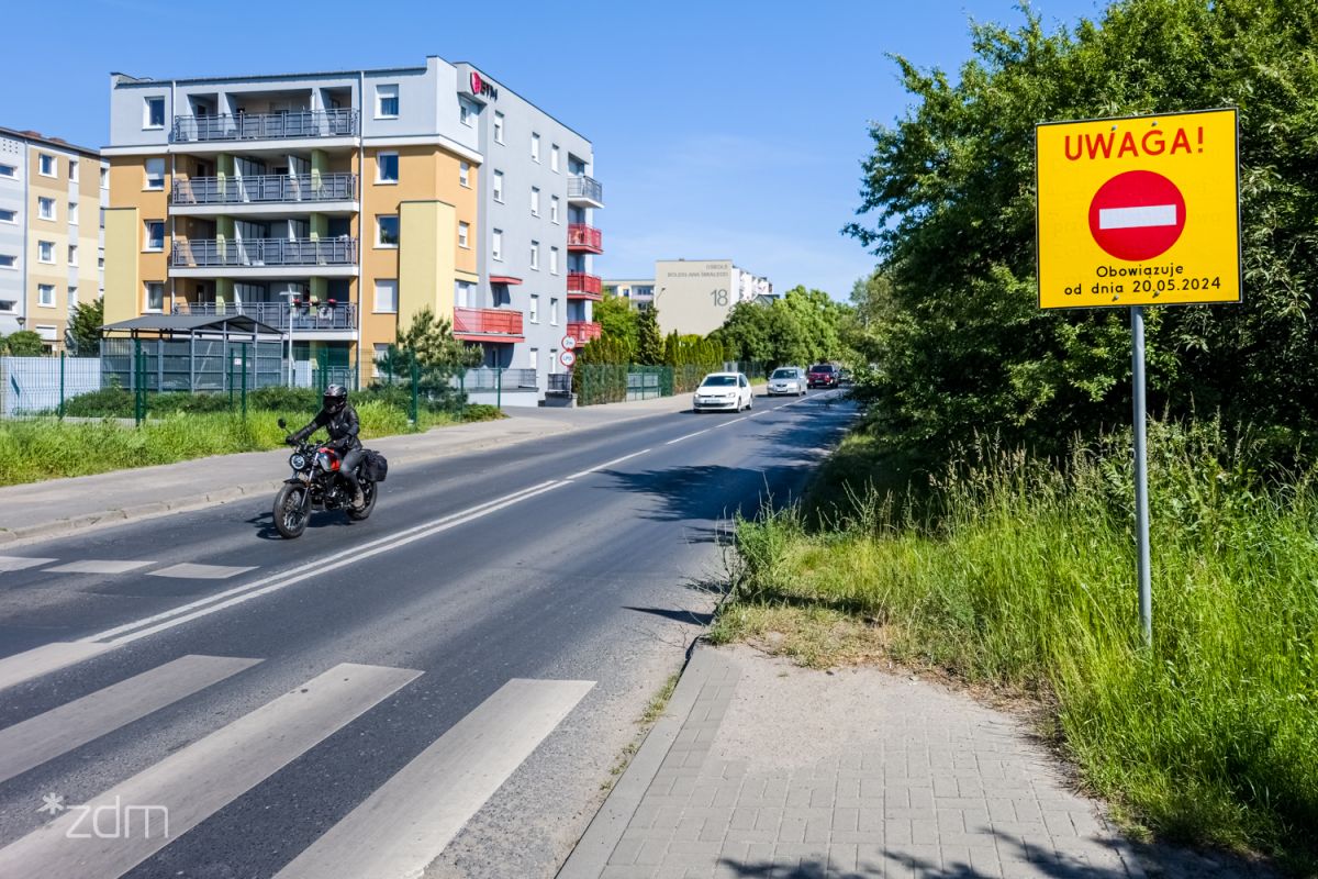 Ulica z jadącym motocyklistą, po prawej stronie znak zakazu wjazdu