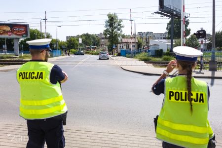 Para policjantów z drogówki patrzący na przejazd przez tory kolejowe