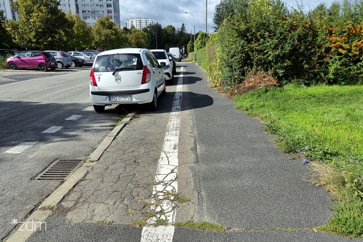 Zniszczona nawierzchnia chodnika i parkujące samochody