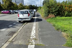 Zniszczona nawierzchnia chodnika i parkujące samochody