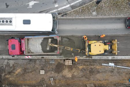 Widok z drona - autobus przejeżdżający obok maszyn drogowców