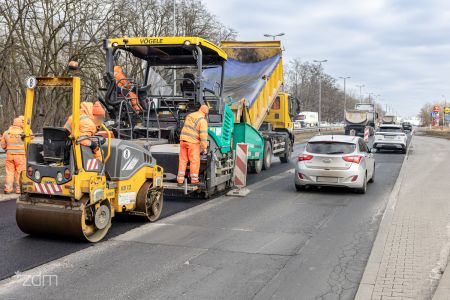 Walec i układarka na lewym pasie jezdni, na prawym jadące samochody