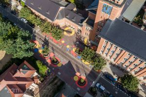 Ulica z lotu ptaka. Jezdnia, dzrewa rosnące przy ulicy i zabudowania