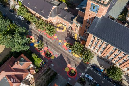 Ulica z lotu ptaka. Jezdnia, dzrewa rosnące przy ulicy i zabudowania