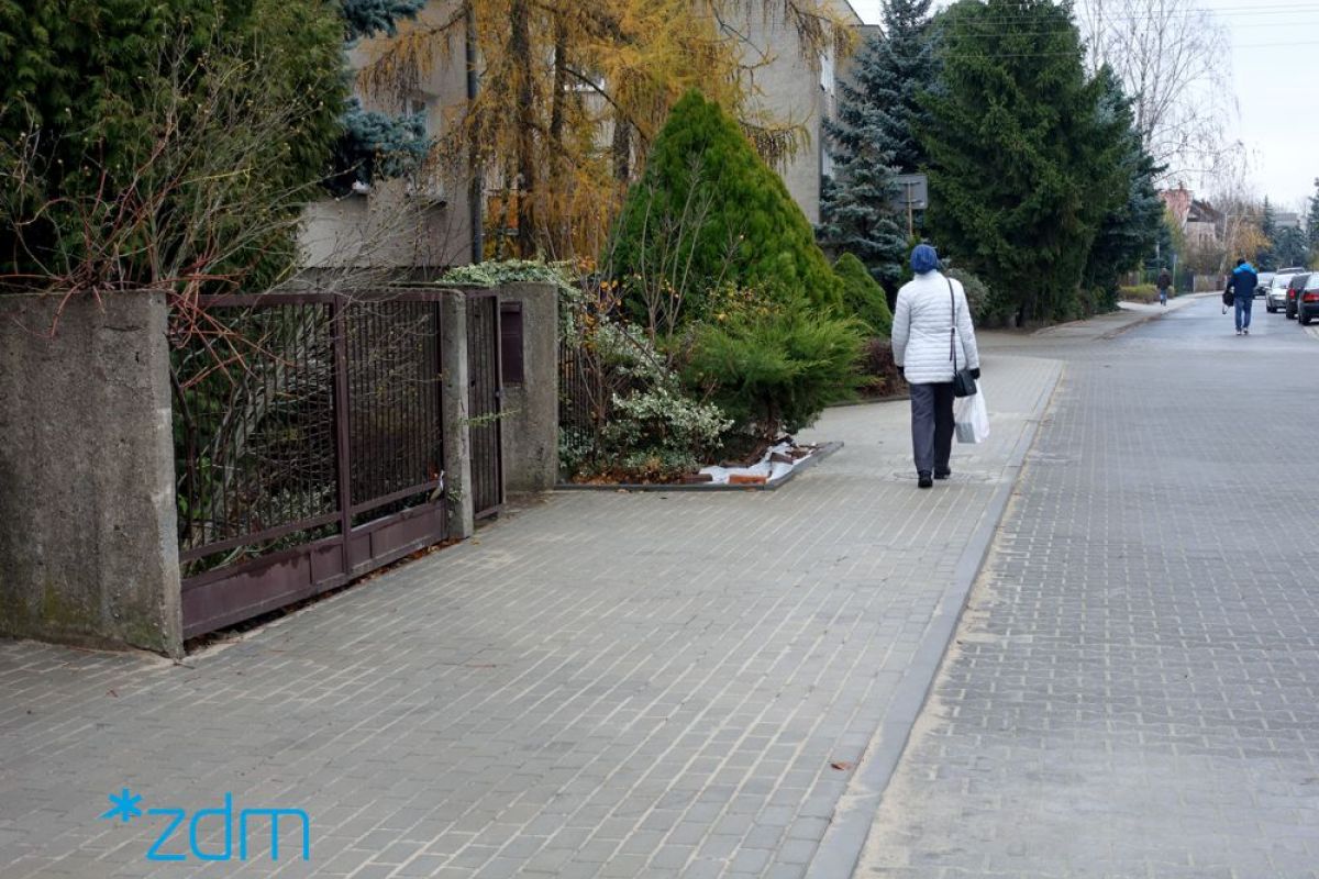 Chodnik na ul. Sołtysiej. Po lewej stronie zieleń, na środku chodnik z pieszą, a po prawej stronie jezdnia