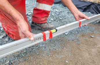 Pracownik z poziomica podczas budowy chodnika. fot. PIM