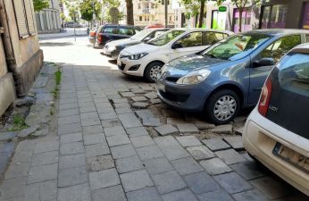 Zniszczony chodnik i parkujące samochody