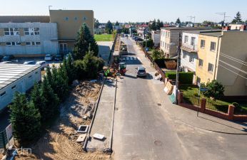 widok z drona na ulicę, po lewej stronie szkoła centralnie budowa chodnika po prawej domy 
