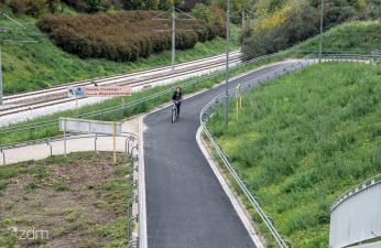 po lewej stronie trasa tramwajowa pst centralnie droga rowerowa z rowerzystką, po prawej skarpa z trawnikiem