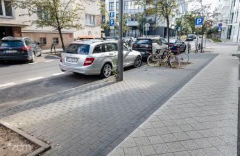 Jezdnia z zaparkowanymi samochodami, chodnik i drzewa