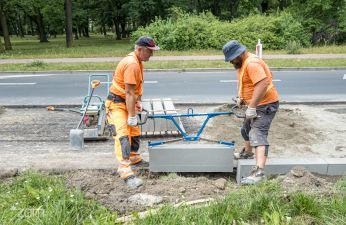 Dwóch robotników przenosi krawężnik