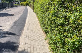 Widok na wyremontowany chodnik na ul. Kępińskiej, z prawej strony widok żywopłotu.