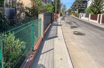 Widok na wyremontowany chodnik na ul. Śmiełowskiej, w tle widoczne płoty i domy.