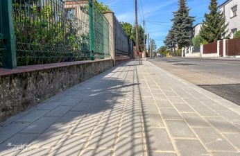 Widok na wyremontowany chodnik na ul. Śmiełowskiej, w tle widoczne płoty i domy.