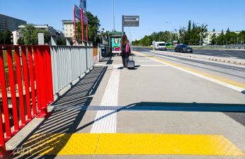 Fakturowe oznaczenia nawierzchni w tle przystanek autobusowy i czekający ludzie