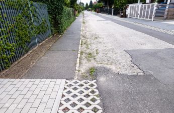 Ulica Notecka widziana z chodnika, z lewej płot i roślinność