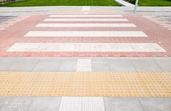 Zbliżenie na nowe przejście dla pieszych wraz z fragmentem chodnika i fakturowych oznaczeń nawierzchni