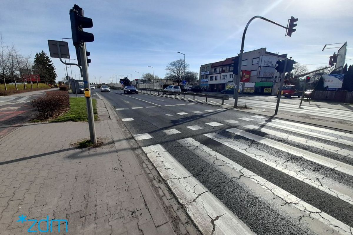 Przejście dla pieszych z sygnalizacją na ul. Głogowskiej. Na jezdni zniszczona nawierzchnia
