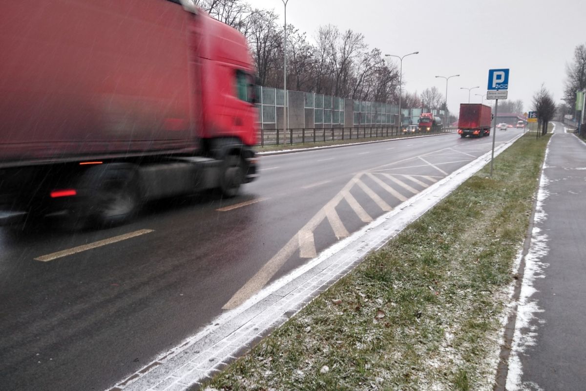 Ciężarówki jadące dwupasmową ulicą i padający śnieg