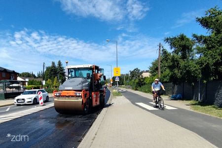 Remont na ul. Strzeszyńskiej, od lewej jadący biały samochód, na pasie obok walec, a z prawej strony rowerzysta