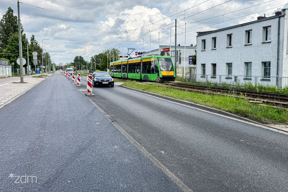 Samochód jadący po wyremontowanej jezdni, po prawej stronie tramwaj.