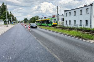 Samochód jadący po wyremontowanej jezdni, po prawej stronie tramwaj.