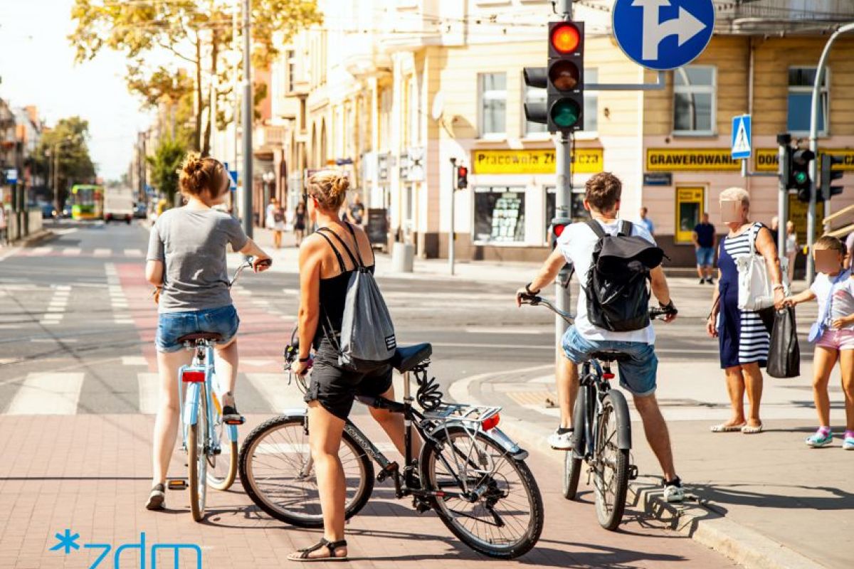 Trzech rowerzystów na drofdze dla rowerów oczekuje na zielone światło na sygnalizatorze