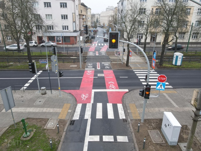 Przejazd przez ul. Hetmańską. Zdjęcia z drona. Po lewej stronie jezdnia, po środku czerwono zaznaczne drogi dla rowerów, po prawej chodnik i jezdnia